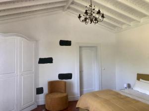 a bedroom with a bed and a chair and a chandelier at La VIGIE de CASTELROCK ( Casa Petunia ) in Mosteiros