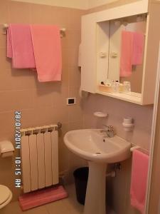 bagno con lavandino, specchio e asciugamani rosa di Hotel Residence La Rosa a Castione della Presolana