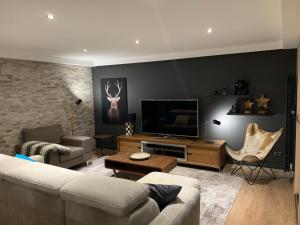 uma sala de estar com um sofá e uma televisão de ecrã plano em Aux Pierres Du Clos - Les 3 Vallées em Brides-les-Bains