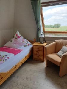 a bedroom with a bed and a chair and a window at Pension To olen Slüüs Dagebüll in Dagebüll