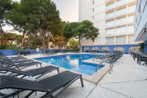 una piscina con tumbonas junto a un edificio en Hotel Torre Azul & Spa - Adults Only, en El Arenal