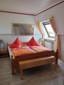 a bedroom with a bed with red pillows and a mirror at Pension To olen Slüüs Dagebüll in Dagebüll