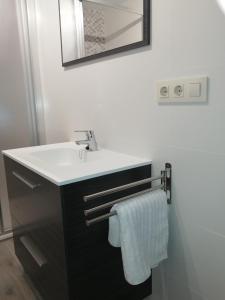 ein Badezimmer mit einem weißen Waschbecken und einem Spiegel in der Unterkunft Apartamento A Fabrica in Santiago de Compostela
