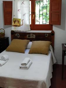 a bed with two towels on it with a window at Cortijo La Solana in Güéjar-Sierra