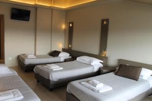 a hotel room with three beds and a flat screen tv at Plus Florence in Florence
