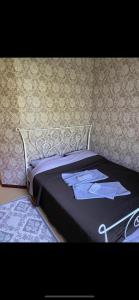 a bed with a black comforter with a shirt on it at Mini Hotel Venezia in Atyrau