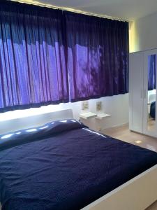 - une chambre avec un grand lit et des rideaux violets dans l'établissement Portorosa, à Torre Forte
