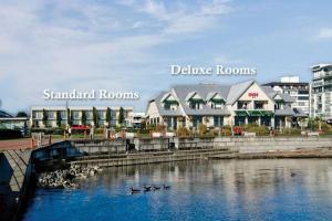 un grupo de patos en el agua frente a los edificios en Sidney Waterfront Inn & Suites, en Sidney