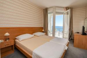 - une chambre avec un grand lit et un balcon dans l'établissement Hotel Neva, à Podstrana