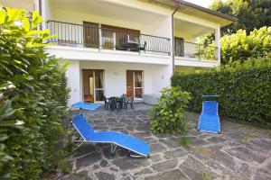 un patio con sillas azules y una casa en Casa Magnolia en Luino