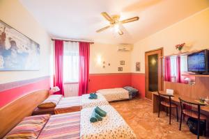 Habitación con 2 camas, mesa y ventilador de techo. en Aurora Rooms, en Lecce