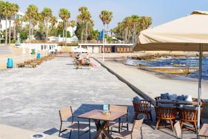 a group of tables and chairs on a beach at Light House - Seafront cosy studio with library in Paphos City