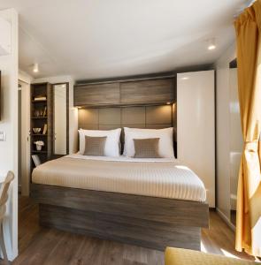 een slaapkamer met een groot bed met een houten hoofdeinde bij Victoria Mobilehome in Padova Premium Camping Resort in Banjol