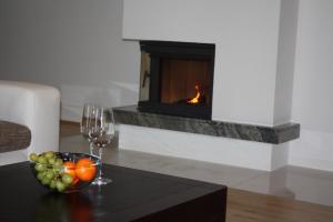a wine glass and a bowl of fruit on a table with a fireplace at Villa Malina in Oščadnica