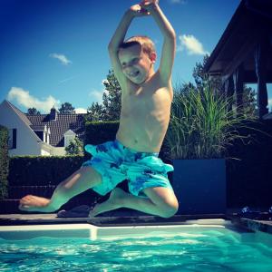 Un jeune homme saute dans une piscine dans l'établissement Romantik B&B Zonnehuis, au Coq