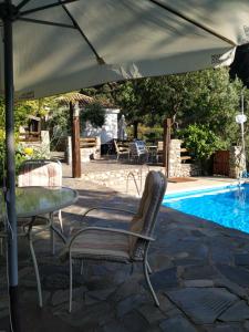 una mesa y sillas bajo una sombrilla junto a la piscina en Cortijo La Solana, en Güéjar-Sierra