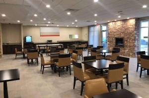 a dining room with tables and chairs and a stone wall at Hawthorn Extended Stay by Wyndham Monahans in Monahans