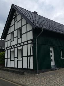 un bâtiment noir et blanc avec un toit vert dans l'établissement Fewo Eifeler Edelsteine „Aquamarin“, à Schleiden
