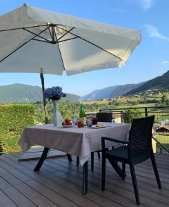 un tavolo e sedie con ombrellone su una terrazza di L' aurora a Pieve Tesino