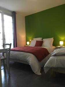a bedroom with a large bed with a green wall at Ô MARRONNIER de NADAILLAC in Nadaillac