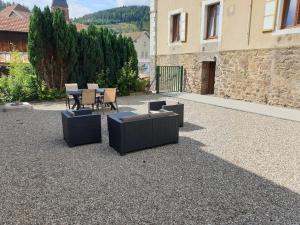 a patio with chairs and tables and a building at Au Pied du Gazon in Saint-Maurice-sur-Moselle