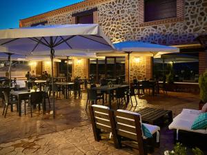 un restaurante con mesas, sillas y sombrillas en Hotel Rural La Cabrera, en Robledo del Buey
