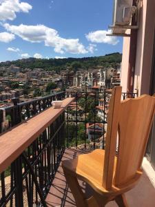 a wooden chair sitting on a balcony overlooking a city at Hotel Stambolov in Veliko Tŭrnovo