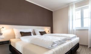 um quarto com uma cama grande com lençóis brancos e uma janela em Gästehaus Lemerhof em Oberding