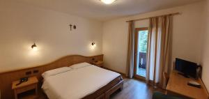 sypialnia z białym łóżkiem i telewizorem w obiekcie Hotel Diana w mieście Canazei