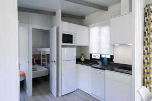 a white kitchen with white cabinets and a sink at Tamarit Beach Resort in Tamarit