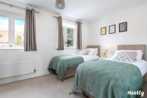 2 camas en un dormitorio con paredes y ventanas blancas en Albatross House - Comfy Home with Parking en Slough