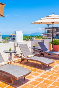 a patio with chairs and tables and an umbrella at Tres Marias Luxury Suites - Adults Only in Puerto Vallarta