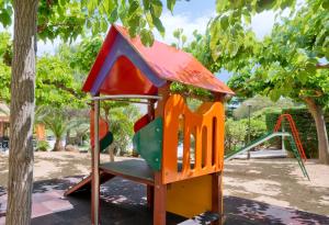 een speeltuin in een park met een boom bij GHT Aparthotel Tossa Park in Tossa de Mar