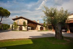 una casa con un albero di fronte a un vialetto di Wine Resort Luisa a Mariano del Friuli