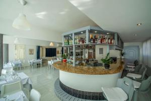 ein Restaurant mit einer Bar mit weißen Tischen und Stühlen in der Unterkunft Hotel Plaza Europa in Sosúa
