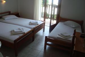 a room with two beds and a balcony with a window at Hotel Sevilli in Agios Ioannis Pelio