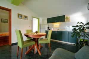 uma cozinha com uma mesa de madeira e cadeiras verdes em House Klarin em Jezera