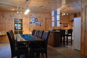 a dining room with a table and a refrigerator at Les Chalets du Lac Serein (Milot) in Saint Ludger de Milot