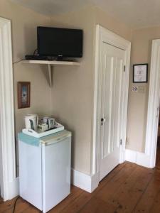 a kitchen with a tv on the wall and a refrigerator at Fisherman's Daughter B&B in Mahone Bay