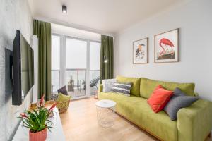 salon z zieloną kanapą i telewizorem w obiekcie BellMi Apartamenty - Parking Gratis, Plaża 5min, Komfort i Relaks w Kołobrzegu