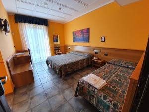 a hotel room with two beds and yellow walls at Hotel Azalea in Baveno