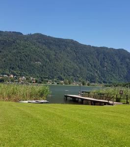 a dock in the middle of a lake with a mountain at Ferienwohnung Claudia in Altossiach