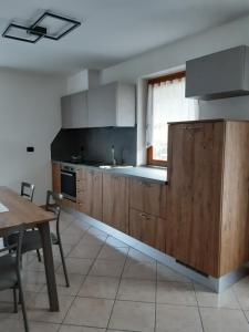 una cucina con armadi in legno, tavolo e finestra di Appartamento Paganella ad Andalo