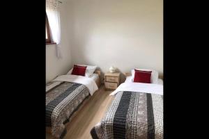 two beds in a small room with red pillows at Domek Polny czar in Pogorzelica