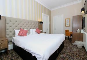 a hotel room with a large bed with red pillows at Ambassador Hotel in Glasgow