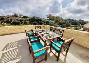 een houten tafel en stoelen op een patio bij Id-Dar tar-Rizzi Holiday Home in Victoria