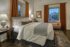 a bedroom with a large bed and a chair at Armory Park Inn in Tucson