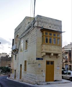 un antiguo edificio de piedra con ventanas amarillas en una calle en Id-Dar tar-Rizzi Holiday Home en Victoria