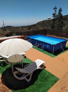 una mesa, una silla y una sombrilla junto a la piscina en Casa Roque, en Telde