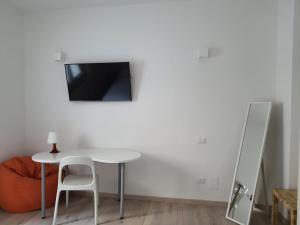 einen weißen Tisch mit einem Stuhl und einen TV an der Wand in der Unterkunft Isabella d'Aragona Guest House in Barletta